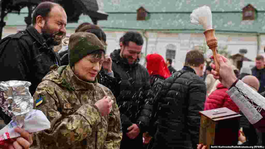 Священник ПЦУ освячує&nbsp;&nbsp;водою вірян та їхні великодні кошики після служби в Успенському соборі Києво-Печерської лаври