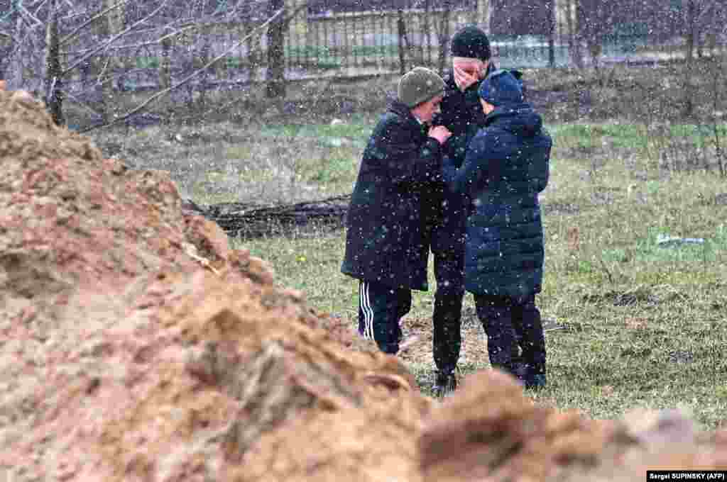 Люди плачуть біля одного із масових захоронень жертв російських військових. Буча, 3 квітня 2022 року. За повідомленням офіційного Києва, 175 загиблих людей знайшли у Бучі у різних місцях масових захоронень й катівнях&nbsp;