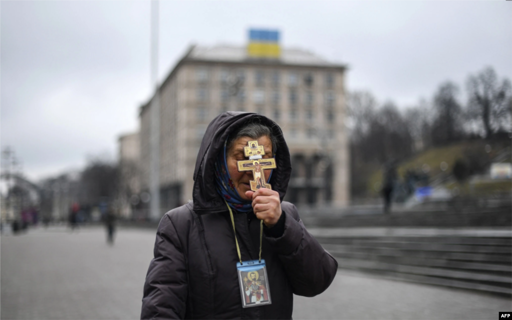 Жінка тримає хрест під час молитви на майдані Незалежності в Києві вранці 24 лютого