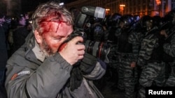 Украина милициясының операциясы кезінде басынан жараланған Reuters фототілшісі Глеб Гаранич Тәуелсіздік алаңындағы оқиғаны суретке түсіріп тұр. Киев, 30 қараша 2013 жыл.