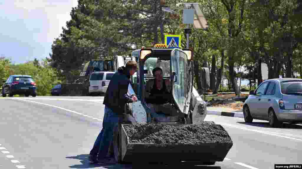 Будівельники возять бетон у ковші міні-бульдозера прямо трасою, що проходить через Сапун-гору