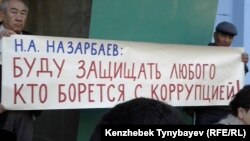 Президент Назарбаевтың сөзі жазылған плакат ұстаған белсенділер Алматы қалалық сотының алдында наразылық акциясында тұр. 17 қыркүйек 2013 жыл.