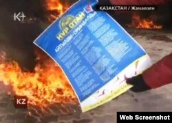 Жұмысшы киімін киген адам «Нұр Отан» партиясының плакатын отқа тастап жатыр. Жаңаөзен, 16 желтоқсан, 2011 жыл. ((К-плюс телеарнасы бейнехабарынан алынған скриншот).