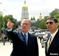 Колишній президент США Джордж Буш (ліворуч) під час приватної поїздки до України у центрі української столиці разом із тодішнім послом в Україні Джоном Едвардом Гербстом. Київ, 21 травня 2004 року