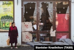 Жінка стоїть біля магазину, пошкодженого обстрілами під час воєнного конфлікту, в Степанакерті (Ханкенді), столиці сепаратистського Нагірного Карабаху. 4 листопада 2020 року