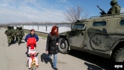 Әскерилер мінген көлік қасынан өтіп бара жатқан әйелдер. Симферополь, 14 наурыз 2014 жыл