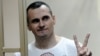 RUSSIA – Oleh Sentsov gestures as the verdict is delivered as he stands behind bars at a court in Rostov-on-Don, August 25, 2015